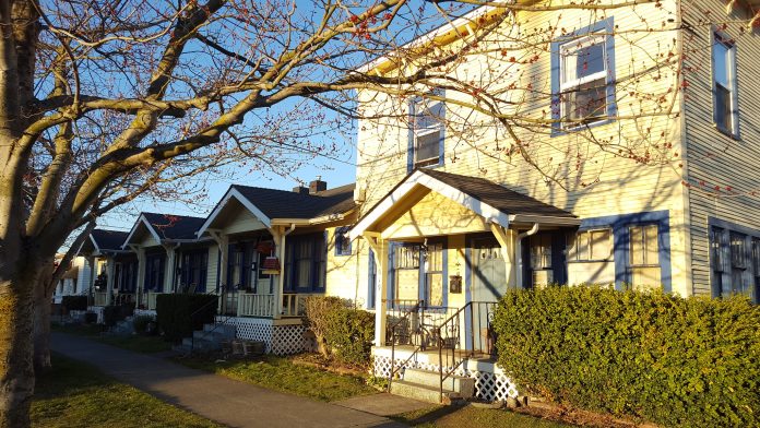 48104449522_824e5446ff_o a photo of a small apartment building next to cottages