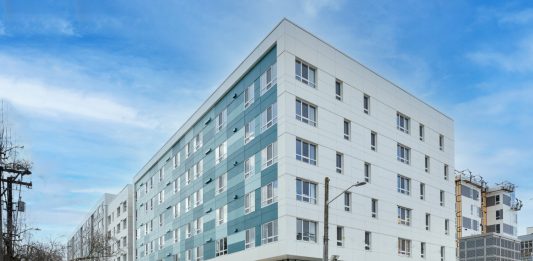 a photo of a modern aqua and white five story apartment building