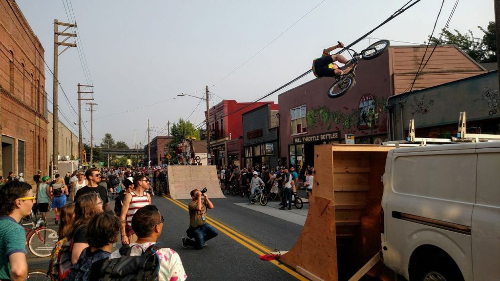 A half-pipe is set up on Airport Way S closed to cars and a guy in a bike gets some serious air off of it as a crowd people looks on.