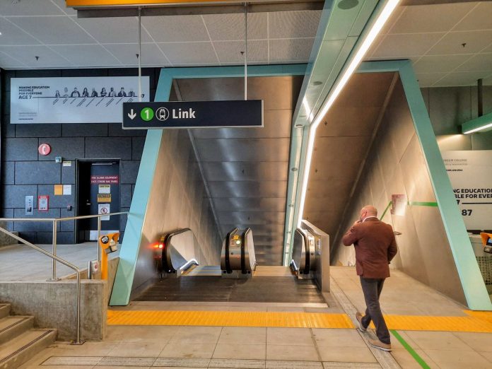 A man walks toward the escalator down to the station platform.