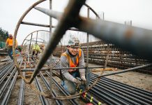 Concrete Could Flow for West Seattle Bridge and Light Rail Projects as Teamsters Offer to Return to Work An ironworker stands inside a big rebar column and smiles for the camera.