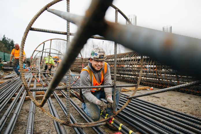 An ironworker stands inside a big rebar column and smiles for the camera.