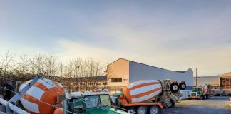 A gravel lot with three concrete mixer trucks.