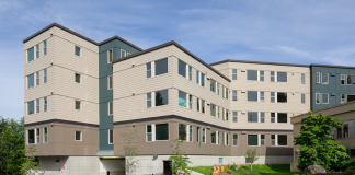 A view of a an apartment building in front of a green lawn.