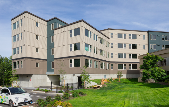 A view of a an apartment building in front of a green lawn.