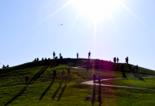 Achieving New Heights: Spring 2022 Publication Update a photo of people standing on a green hill under a blue sky