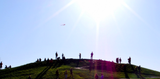 Achieving New Heights: Spring 2022 Publication Update a photo of people standing on a green hill under a blue sky