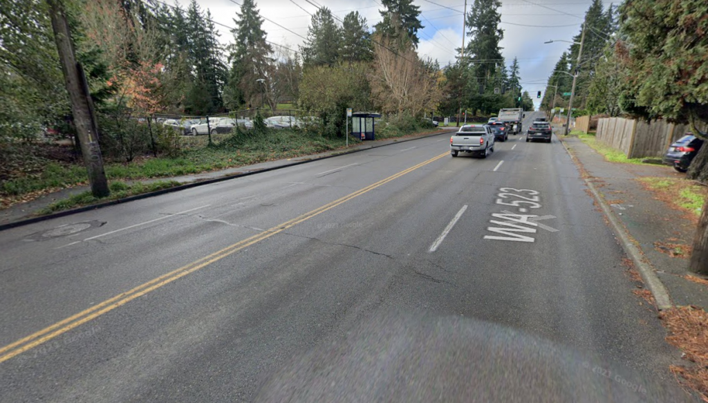 Street view of four lane road with crappy sidewalks and no curb ramps