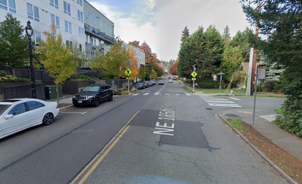 A two lane street with wide lanes and street parking and curb bulbs