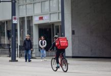 Corporations Push Back As Details Emerge on Seattle’s Pay Up Legislation for App-Based Workers A bicycle delivery worker with a red bag.