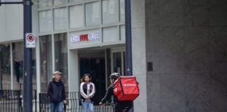 A bicycle delivery worker with a red bag.