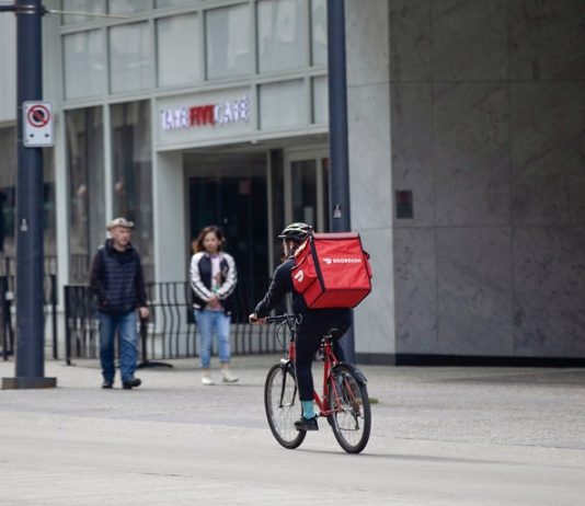 Corporations Push Back As Details Emerge on Seattle’s Pay Up Legislation for App-Based Workers A bicycle delivery worker with a red bag.