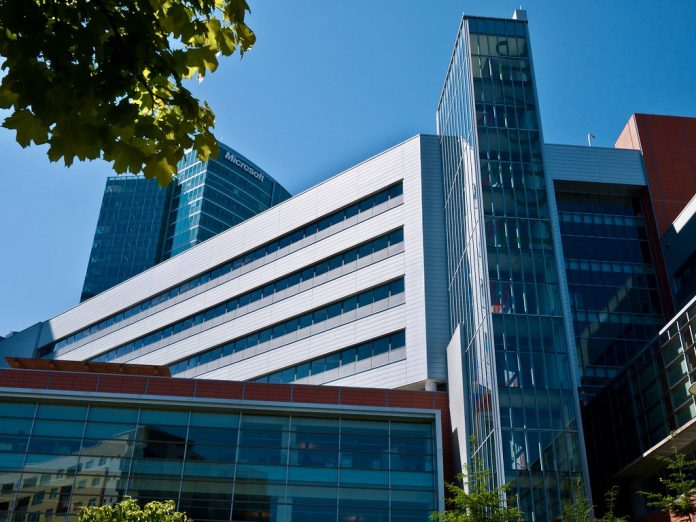 A photo of a large modern building with a leafy tree branch in front of it.