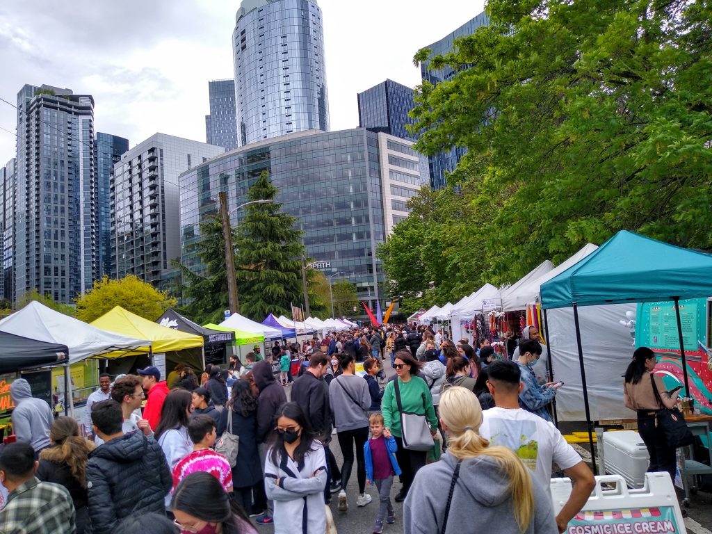 A crowd of people along a street with vendors and tents