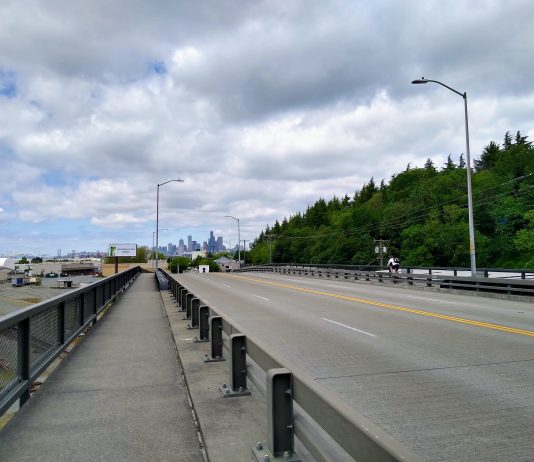Plans Advance for a Safe Bike Route Between SoDo and Georgetown A photo of a narrow sidewalk separated from a roadway by a metal rail.