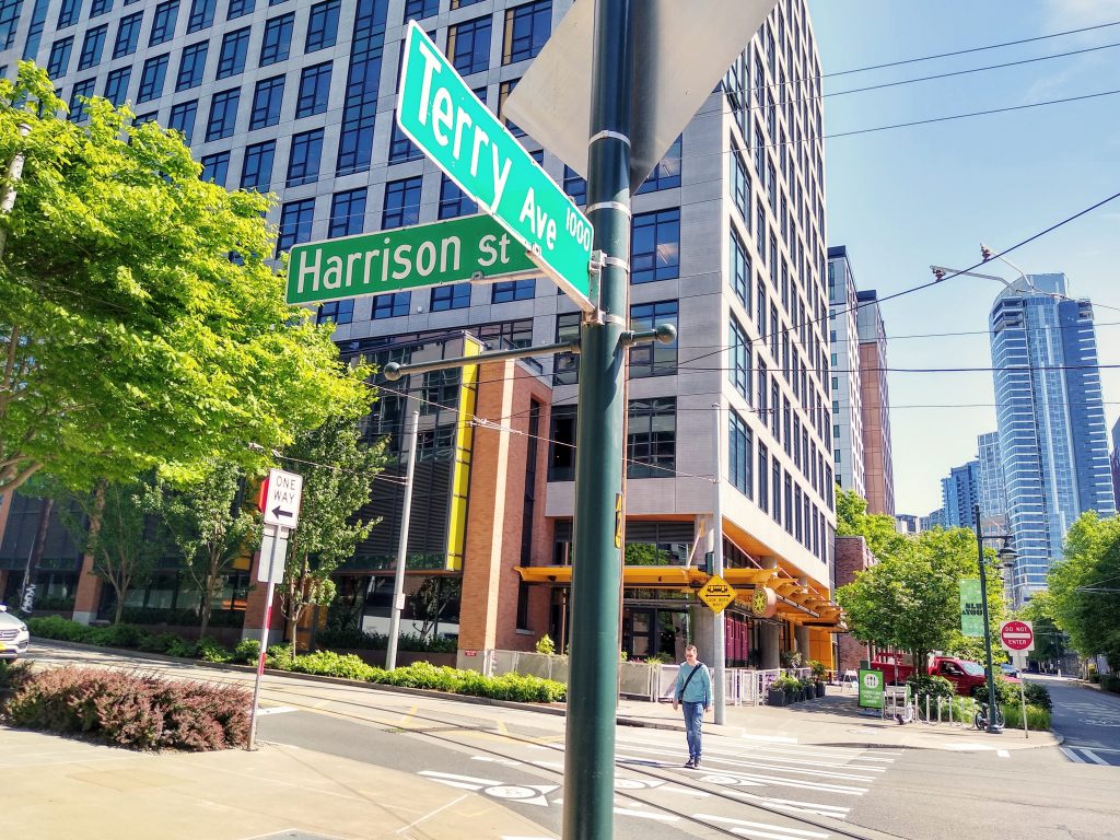 Person crossing the street along Terry Ave near a street sign that reads Terry Ave and Harrison Street