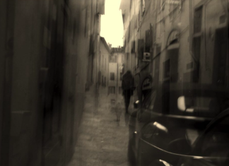 The View From Nathan’s Bus: The Glue That Holds Us Together A blurred black and white photo of a figure walking down a street and a car.