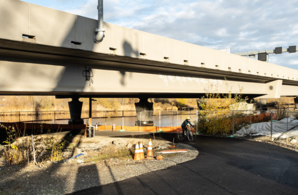 Photo of a person on a bike using the trail under the highway