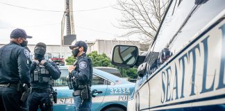 New Seattle Police Contract Punts on Accountability, Delivers Big 23% Raise Three officers standing around a squad car