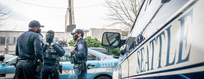 Three officers standing around a squad car