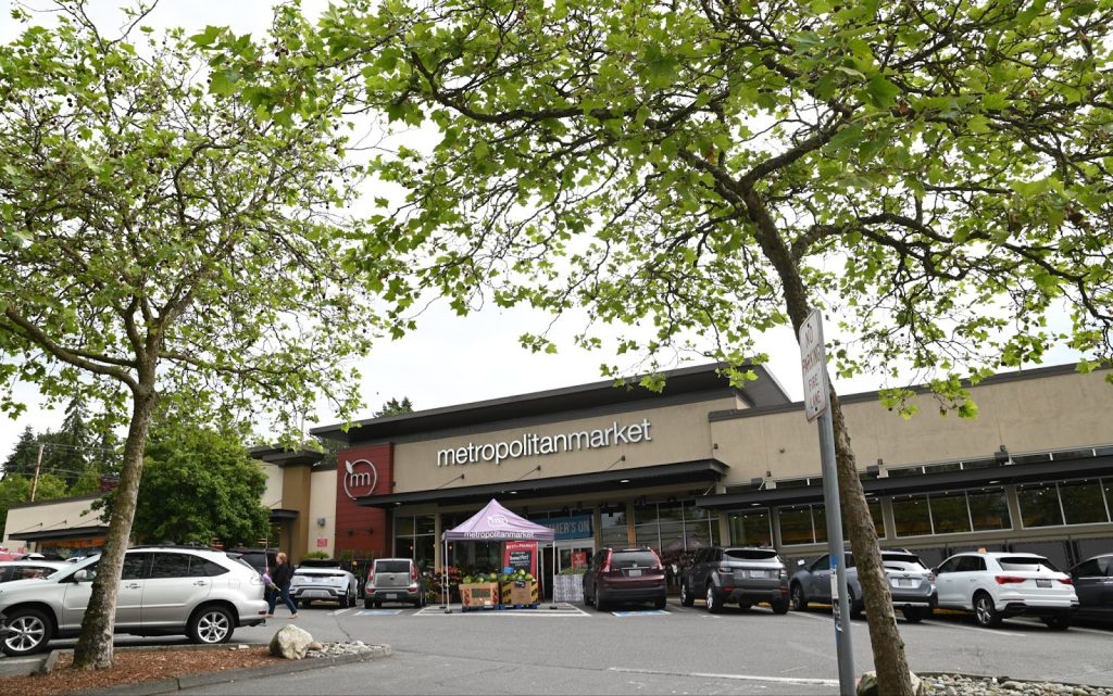 A photo a grocery store with a parking garage and trees. 