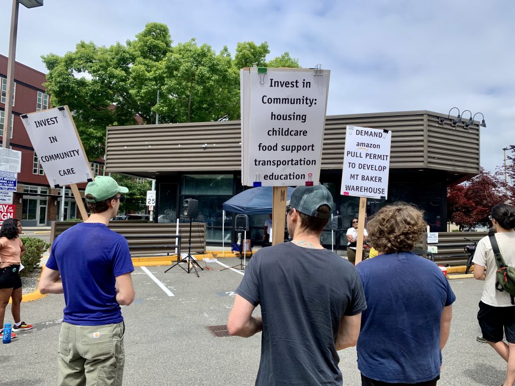 people stand in a parking lot holding stands calling for more community investment