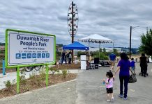 New Park Offers a Glimpse of a Healthier Duwamish River a sign for duwamish people's park with a woman and young child walking by