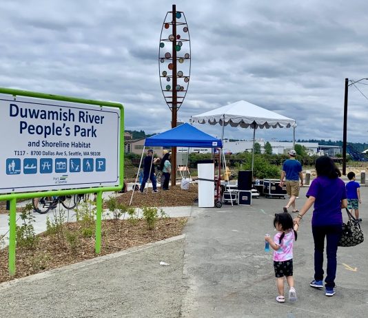 New Park Offers a Glimpse of a Healthier Duwamish River a sign for duwamish people's park with a woman and young child walking by