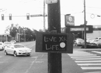 The View From Nathan’s Bus: Doin’ You Black and white photo of a large surface intersection and turning car with a telephone pole right in the middle bearing a sign saying "Live Your Life"