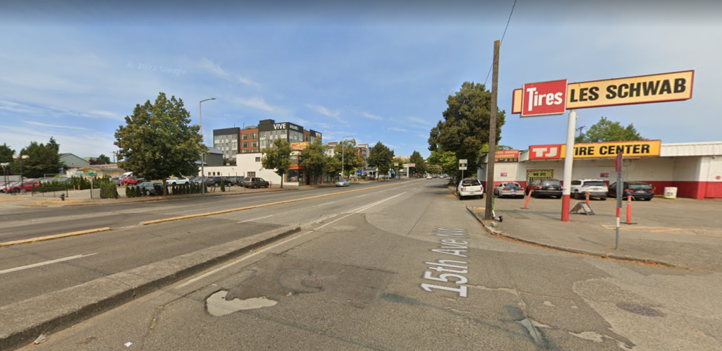 A crossing across six lanes of traffic next to a Les Schwab with a curb indicating a ramp onto a highway