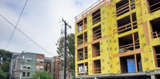 A five story building with yellow insulation before siding is added.