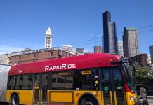 County Council Grapples With Future of King County Metro in Proposed Budget A red and gold RapidRide bus in Pioneer Square with the Seattle skyline in the background.