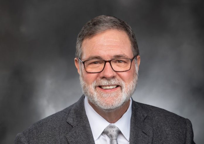 A middle aged man with glasses and a grey beard.