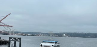 Elliott Bay view of a water taxi arriving at Colman Dock downtown Seattle on a very cloudy day.