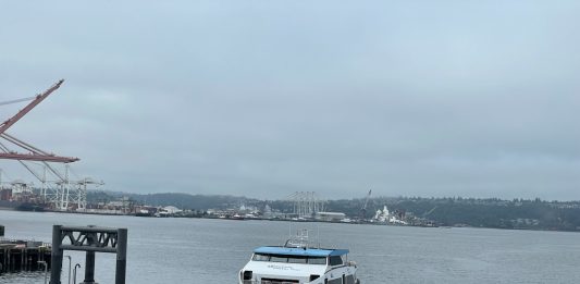 Elliott Bay view of a water taxi arriving at Colman Dock downtown Seattle on a very cloudy day.