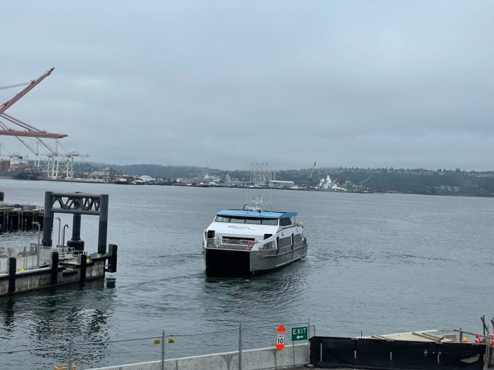 Elliott Bay view of a water taxi arriving at Colman Dock downtown Seattle on a very cloudy day.