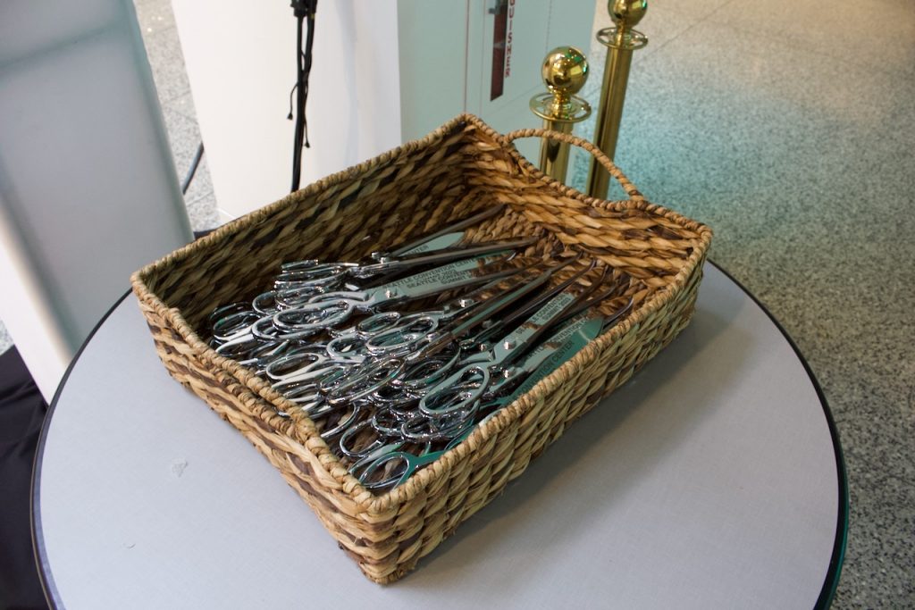 A basket of scissors for a ribbon cutting on a round table.