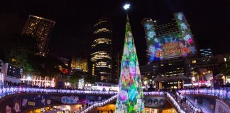 Brightly colored Christmas lights and a Christmas tree in the center of a transit station.