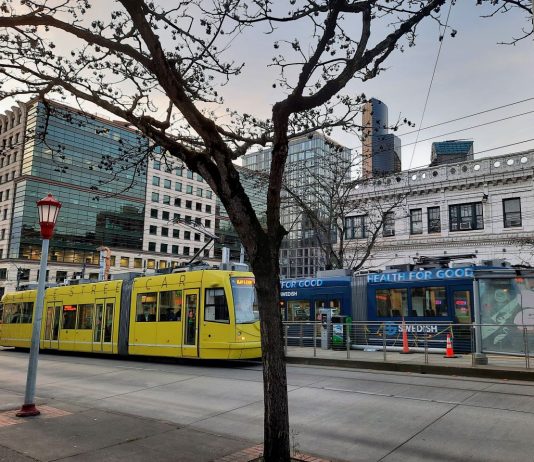 Streetcar Project Could Kickstart Downtown Recovery Two streetcars pass on Jackson Street with the downtown skyline in the background.