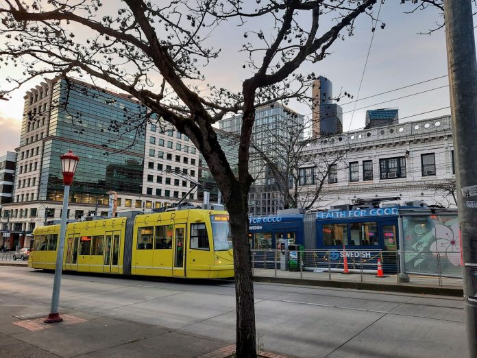 Two streetcars pass on Jackson Street with the downtown skyline in the background.