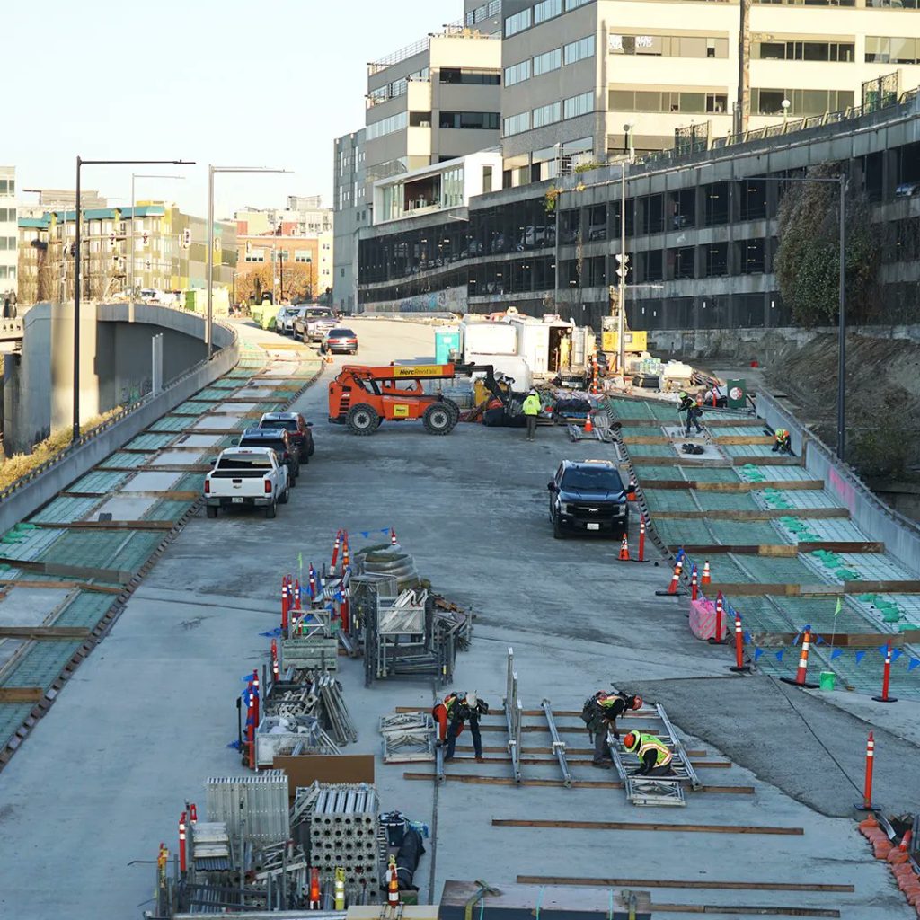 The new four lane road being built with bike lanes and sidewalks visible on the sides