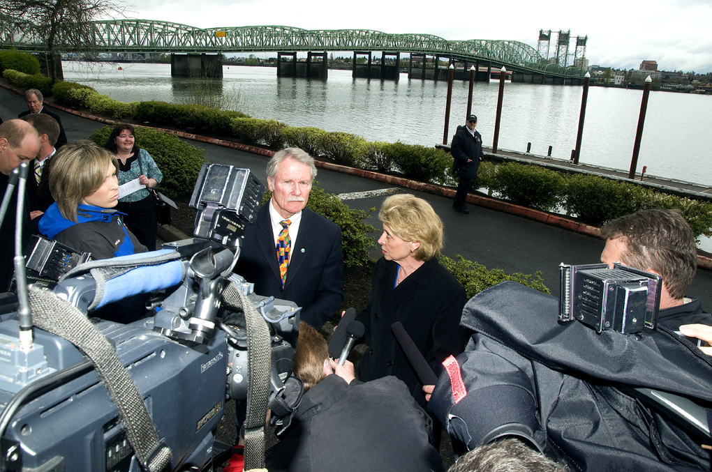 The two governors surrounded by TV cameras looking at each other, with the interstate bridge in the background