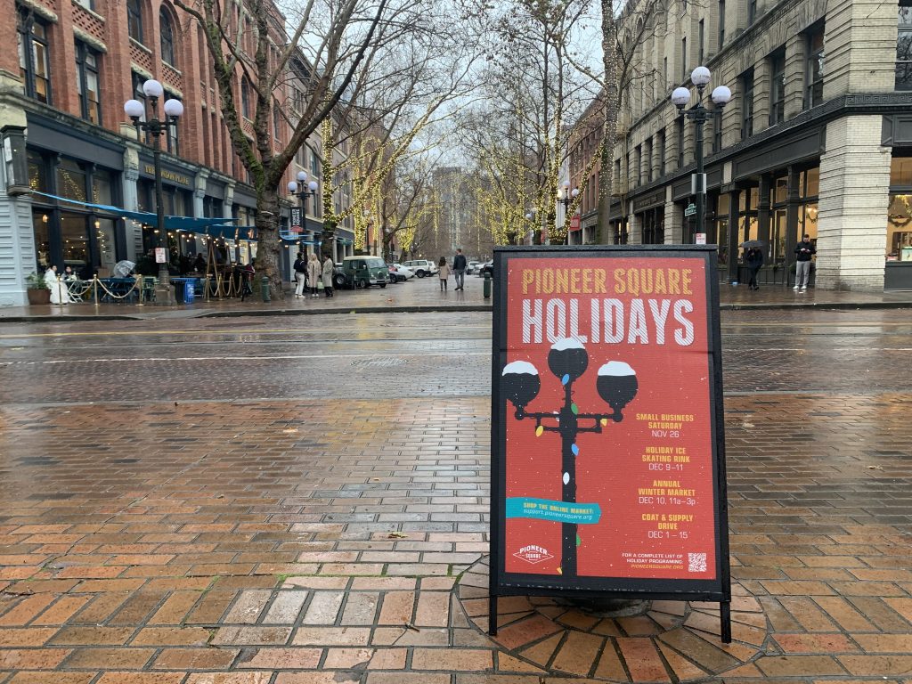 A sign advertising the Pioneer Square holidays in front of a vacant plaza. 