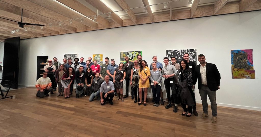 A group of about 40 poses in an art gallery.
