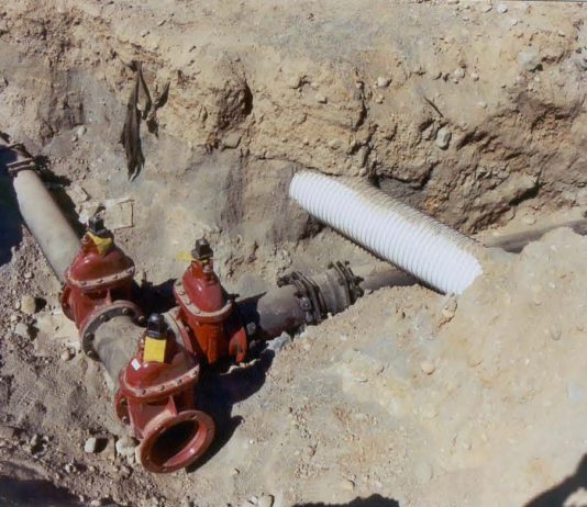 The Urbanist Podcast: How to Crush a Housing Project the Seattle Way Trench cut in dirt with an intersection of iron pipes and a lightly colored stormwater crossing.