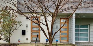 two doors with addresses with a tree in the center and drive with garage in back