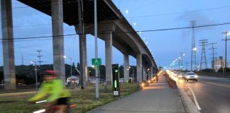 Op-Ed: Vote Yes on Seattle Prop 1 to Save Lives The low bridge stands at dusk with the high bridge above it, and a cyclist is coming off the bridge and is blurred by motion