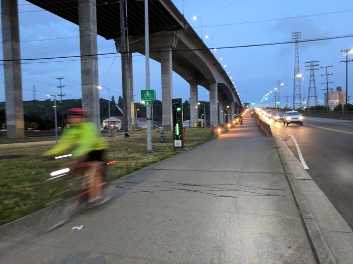 West Seattle low bridge closure The low bridge stands at dusk with the high bridge above it, and a cyclist is coming off the bridge and is blurred by motion