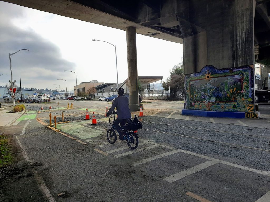 Gravel borders the turn on the waterfront side, as does a colorful mural of birds and flowers on a bridge support. 