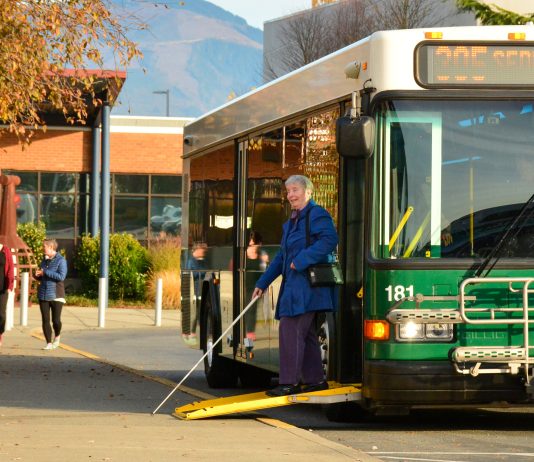 Week Without Driving Goes Nationwide This October – Join Us! A green bus marked Route 305 Sedro Woolley with its ramp out to let a woman with a cane exit.